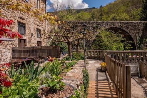an old stone building with an archway in a garden at Rives de Bourges in Burzet