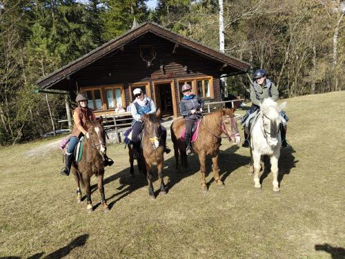 a group of people riding horses in front of a cabin at Reiterbauernhof Maho in Sankt Aegyd am Neuwalde