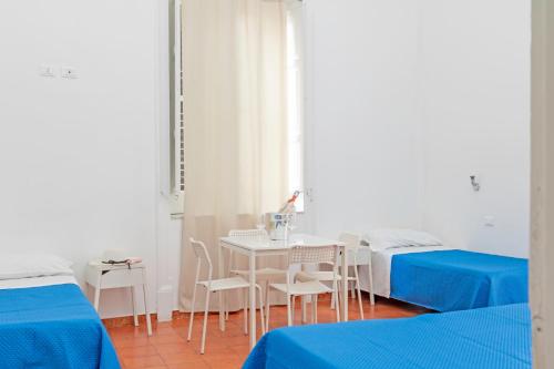 a room with two beds and a table and chairs at A Casa di Amici in Palermo