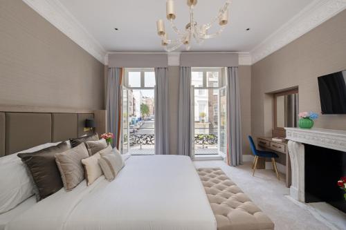 a bedroom with a large white bed and a fireplace at Charles of Mayfair in London