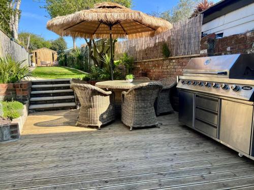 an outdoor patio with a table and an umbrella at Saltwater Stunning Holiday Terraced House Milford on Sea Lymington Sleeps 6 in Milford on Sea