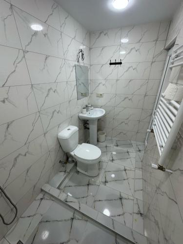 a white bathroom with a toilet and a sink at Hotel Terrace Rabath in Akhaltsikhe