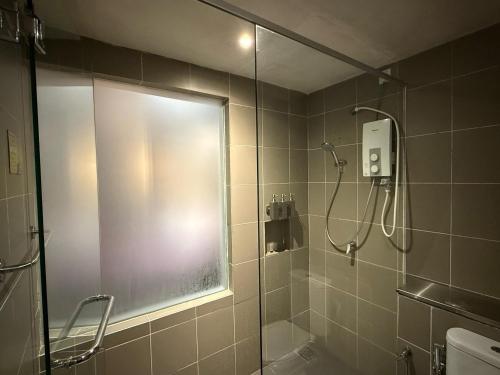 Un baño con ducha con puerta de cristal. en Cosy Residence Homestay 2, en Kota Kinabalu