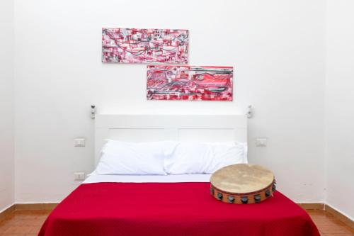 a bedroom with a red bed with two paintings on the wall at A Casa di Amici in Palermo