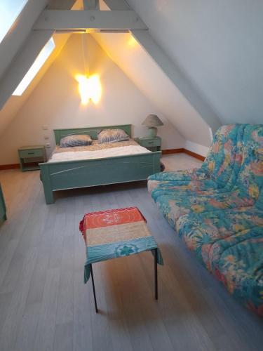 Cette chambre mansardée comprend un lit et un canapé. dans l'établissement Chambre sérénité, à Moult