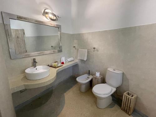 a bathroom with a sink and a toilet and a mirror at Mawe Zuri Resort in Watamu