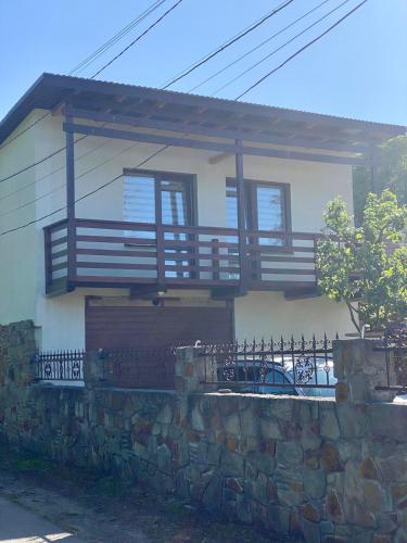 a house with a balcony on top of a stone wall at Dvir in Skole