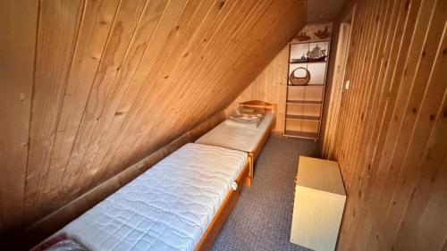 a small room with a bed in a wooden wall at Jaśminowy ogród in Brenna