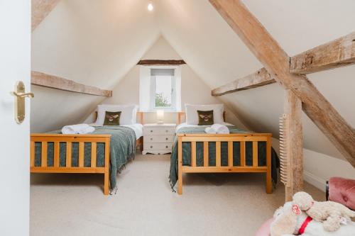 ein Schlafzimmer im Dachgeschoss mit zwei Betten und einem Fenster in der Unterkunft Mulberry Cottage - Stunning 5 Bed in Wiltshire! in Charlton