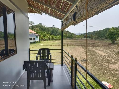 two chairs on a porch with a view of a field at Jolly Homestay in Jog Falls