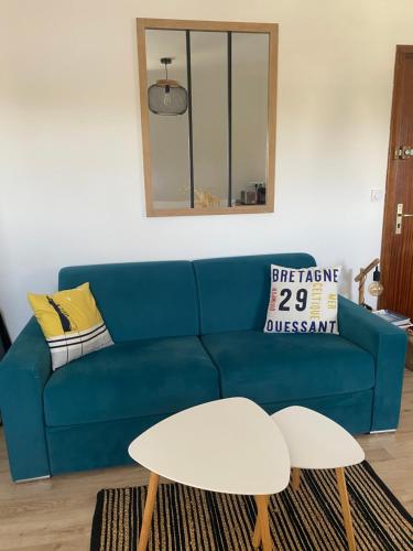 a blue couch in a living room with a mirror at La Brise Marine, calme, Océan, 350m plage in Loctudy
