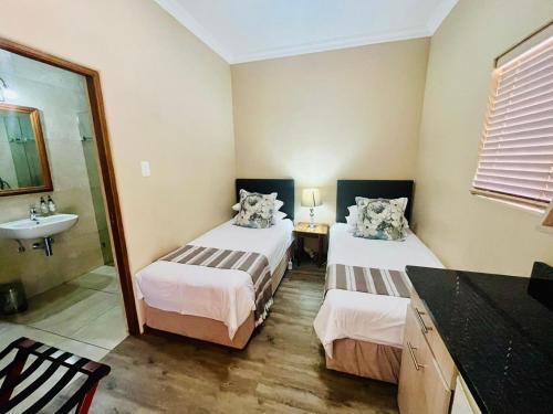 a bedroom with two beds and a sink and a mirror at 17 on Bird Guest House in Beaufort West