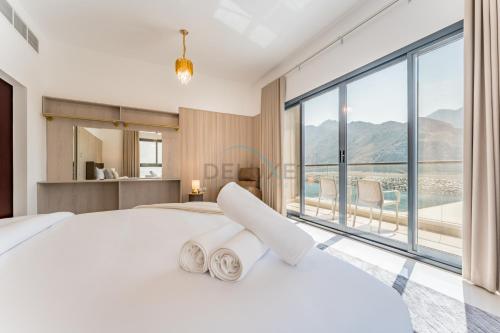 a bedroom with a white bed and a large window at Sea Views 4BR and Assistant's Room Villa with Private Pool, Sharm - Al Dana Villa, Al Dana Island by Deluxe Holiday Homes in Fujairah