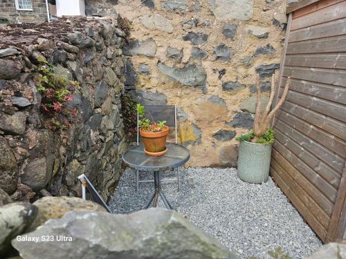a table with two potted plants on it next to a stone wall at Bwthyn Bach Studio in Llanfairfechan