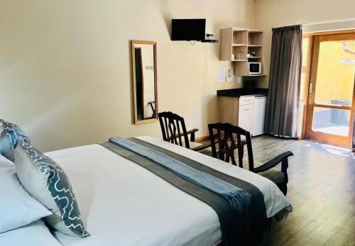a bedroom with a bed with two chairs and a window at 17 on Bird Guest House in Beaufort West