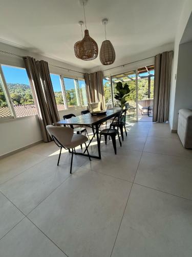 une salle à manger avec une table, des chaises et des fenêtres dans l'établissement Appartement de standing aux portes de Propriano, à Propriano
