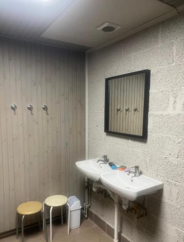 a bathroom with two sinks and two stools and a mirror at Worker hotel ALEJPARKS in Valmiera