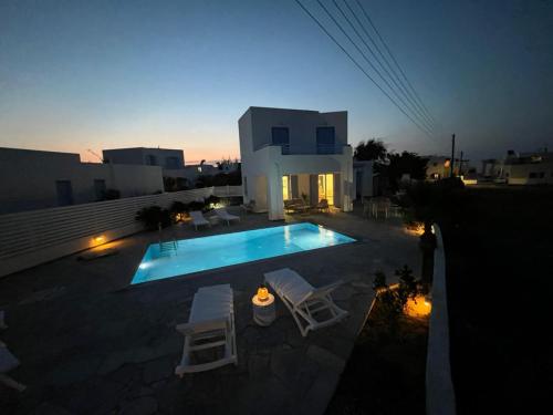 a swimming pool with two chairs and a house at Villa Santorini Serenity with private Pool in Monolithos