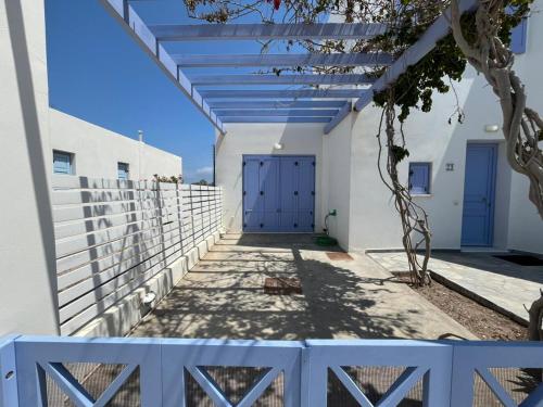a white building with blue doors and a fence at Villa Santorini Serenity with private Pool in Monolithos