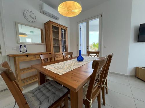 a dining room table with chairs and a blue vase on it at Villa Santorini Serenity with private Pool in Monolithos