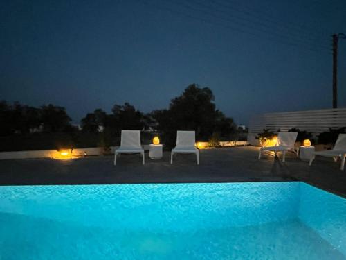 a swimming pool at night with chairs and lights at Villa Santorini Serenity with private Pool in Monolithos