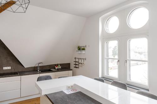 a white kitchen with a table and two windows at Wohnen wie im Schloss - Alter Bahnhof von Kruft in Kruft