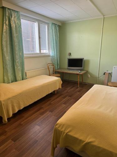 a room with two beds and a desk with a television at Jämsän Gasthaus in Jämsä