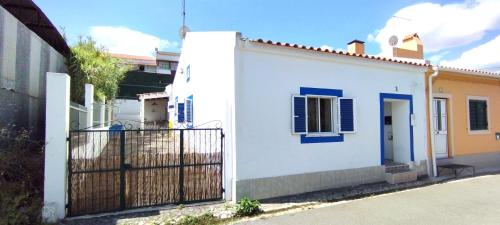 a white house with blue windows and a gate at Casa da Bica in Alvalade