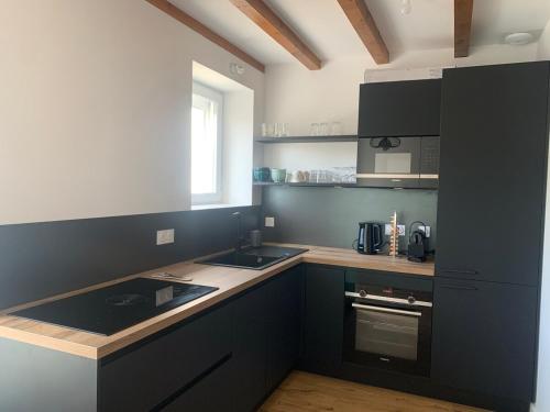 d'une cuisine avec des placards noirs, un évier et une fenêtre. dans l'établissement Les fleurs d Aubrac, à Nasbinals