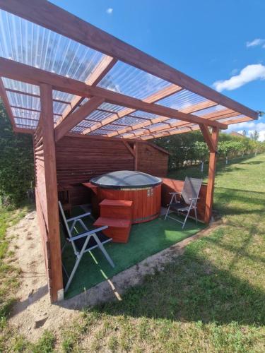 a wooden pergola with chairs and a hot tub at Domki pod Gruszą in Ełk