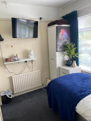 a bedroom with a bed and a tv on the wall at Cornerways Guest House St Austell Cornwall in St Austell
