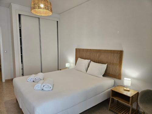 une chambre avec un grand lit blanc avec des serviettes dessus dans l'établissement Apartamento moderno na praia com varanda grande, à Quarteira