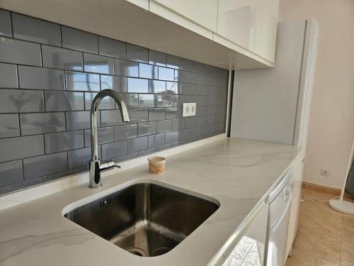 un comptoir de cuisine avec un évier et une fenêtre dans l'établissement Apartamento moderno na praia com varanda grande, à Quarteira