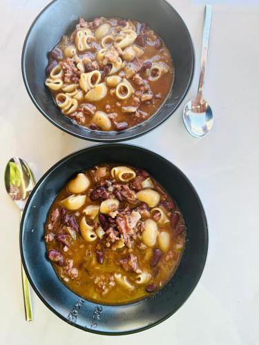 two black bowls of food with beans and pasta at Milton holiday house in Blato