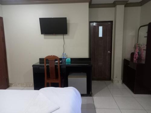 a bedroom with a desk with a computer and a television at Hotel Selver Shinn & Restaurant in Phnom Penh