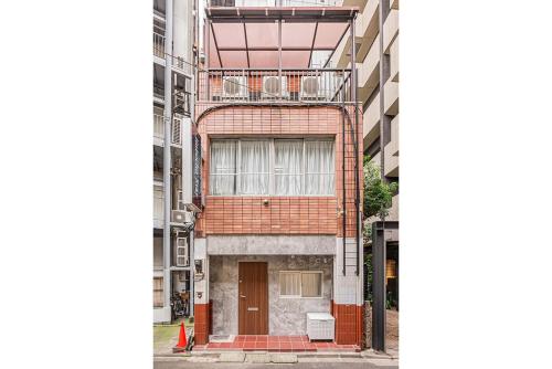 a red brick building with a balcony on a street at 淡路町駅から徒歩1分 140平 4ldk 新宿駅12分 秋葉原5分 東京駅7分 銀座駅7分 渋谷20分 in Tokyo