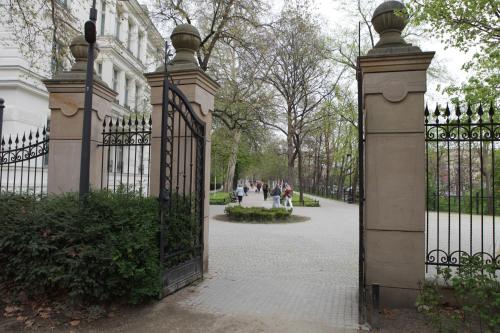 a gate in a park with people walking down a sidewalk at Apartamenty Junior in Wrocław