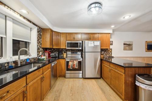 a kitchen with wooden cabinets and stainless steel appliances at Hudson 76I - A Stylish Mountain Retreat in North Creek