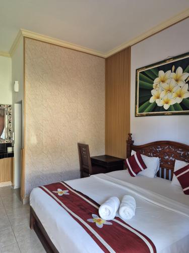 a hotel room with a bed with towels on it at Frangipani Homestay in Nusa Dua