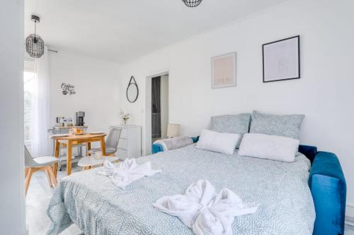 - une chambre blanche avec un lit bleu et une table dans l'établissement Magnifique Appart Cosy Rénové Gare 2 pers, à Gagny