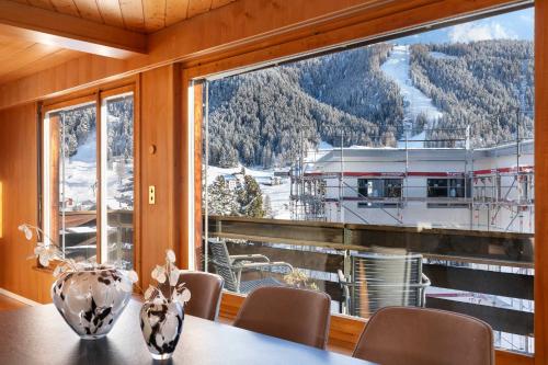 ein Esszimmer mit einem Tisch und einem großen Fenster in der Unterkunft Luxe Davos Residence with Views Private Balcony in Davos