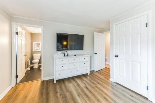 a white bedroom with a tv on a white dresser at Twin Fawns in North Creek