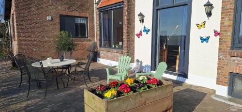 a patio with a table and chairs and flowers in a box at Polderzicht in Ossendrecht