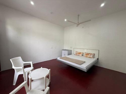 a white room with a bed and two chairs at Sir Mam Ashram in Bhaddi