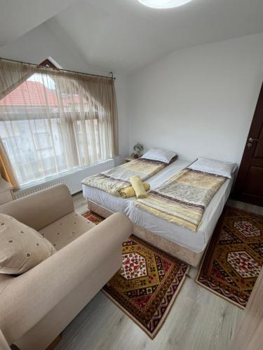 a bed and a couch in a room with rugs at Bayrakova Guest House in Dobrinishte