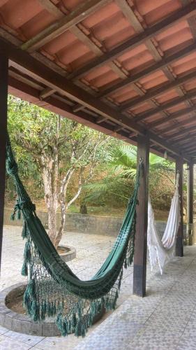 a hammock on a patio with a tree in the background at Suites Sítio do Sol in Penedo