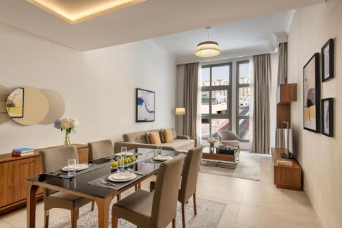 a dining room and living room with a table and chairs at Marriott Executive Apartments Doha, Le Mirage City Walk in Doha
