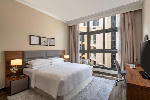 a bedroom with a bed and a desk and a television at Marriott Executive Apartments Doha, Le Mirage City Walk in Doha