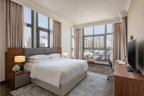 a bedroom with a bed and a desk with a television at Marriott Executive Apartments Doha, Le Mirage City Walk in Doha