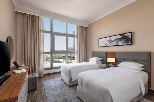 a hotel room with two beds and a television at Marriott Executive Apartments Doha, Le Mirage City Walk in Doha